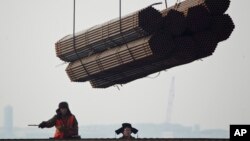 2012年2月20日，在中國唐山曹妃甸港口，工人把鋼管裝船。（資料圖片）