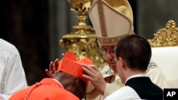 Le pape Francis pose le biretta rouge, chapeau à trois angles, sur la tête du nouveau cardinal du Mali Jean Zerbo lors d’un consistoire dans la basilique Saint-Pierre au Vatican, 28 juin 2017.