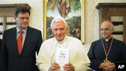 A photo from the Vatican's Osservatore Romano shows Pope Benedict XVI, flanked by German journalist Peter Seewald (L)and by Monsignor Rino Fisichella holding a copy of the book "Light of the World'' at the Vatican, 23 Nov 2010