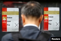 A man looks at a Brexit referendum campaign poster offering a "Pray" option outside a polling station in central London, June 23, 2016.