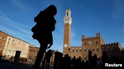 FILE - A woman walks at Del Campo square in Siena, Italy, March 12, 2012.