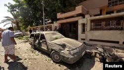 Orang-orang mengamati mobil yang rusak di luar Konsulat Swedia di Benghazi, Libya, sesudah sebuah bom mobil meledak pada 11/10/2013. 