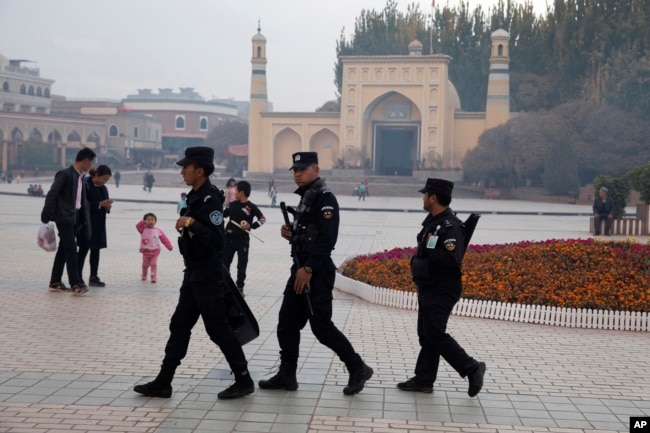 In this Nov. 4, 2017 photo, Uyghur security personnel patrol near the Id Kah Mosque in Kashgar in western China's Xinjiang region.