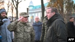 German Defense Minister Boris Pistorius, right, and Colonel Hennadiy Kovalenko are seen after laying flowers on the memorial to the "Maidan Heroes" at Maidan square in Kyiv on Nov. 21, 2023.
