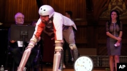 Thomas Thwaites, left, prepares to speak after receiving the Ig Nobel prize in biology from Nobel laureate Eric Maskin (economics, 2007) during ceremonies at Harvard University in Cambridge, Mass., Thursday, Sept. 22, 2016. Thwaites, of the United Kingdom, won for creating prosthetic extensions of his limbs that allowed him to move like and to roam in the company of goats. (AP Photo/Michael Dwyer)