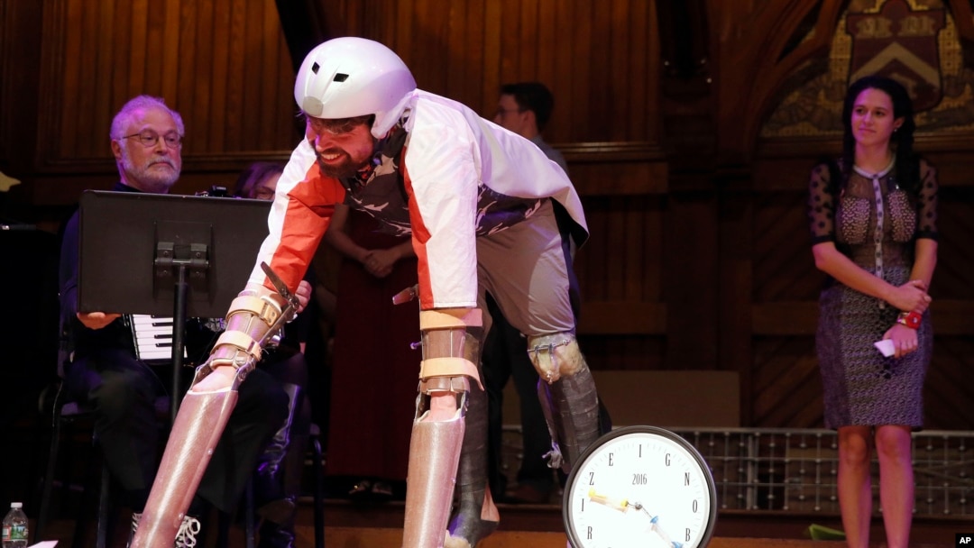 Thomas Thwaites, left, prepares to speak after receiving the Ig Nobel prize in biology from Nobel laureate Eric Maskin (economics, 2007) during ceremonies at Harvard University in Cambridge, Mass., Thursday, Sept. 22, 2016. Thwaites, of the United Kingdom, won for creating prosthetic extensions of his limbs that allowed him to move like and to roam in the company of goats. (AP Photo/Michael Dwyer)