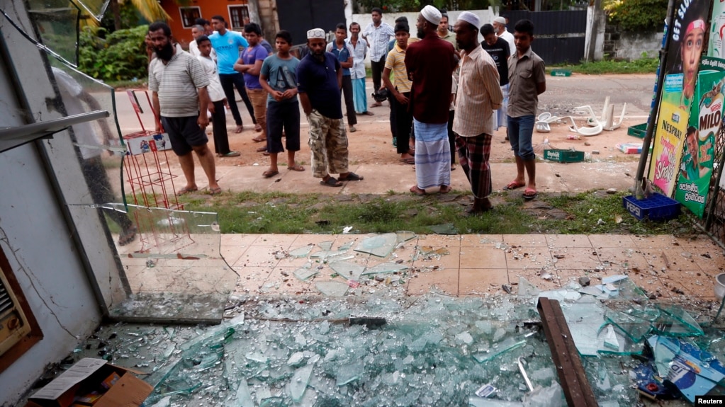 FILE - Muslims stand next to a burnt shop after a clash between Buddhists and Muslims in Aluthgama, Sri Lanka, June 16, 2014. 