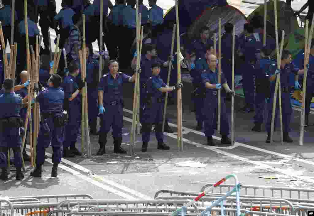 Police officers remove the bamboo barriers that protesters set up to block off main roads in Central district in Hong Kong, Oct. 14, 2014.