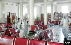 This undated picture released from North Korea's official Korean Central News Agency, Feb. 15, 2020, shows people in protective suits spraying disinfectant at an undisclosed location in North Korea amid concerns about the coronavirus.