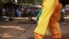 Un membre de la Croix-Rouge française désinfecte la zone autour d'une personne immobile soupçonnée d'être porteuse du virus Ebola à Forecariah, en Guinée, le 30 janvier 2015.