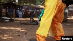 Un membre de la Croix-Rouge française désinfecte la zone autour d'une personne immobile soupçonnée d'être porteuse du virus Ebola à Forecariah, en Guinée, le 30 janvier 2015.