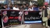 FILE - An employee of a local television channel shows a picture of slain journalist Aziz Memon on his mobile, after a demonstration to condemn his killing, in Hyderabad, Pakistan, Feb. 17, 2020. 