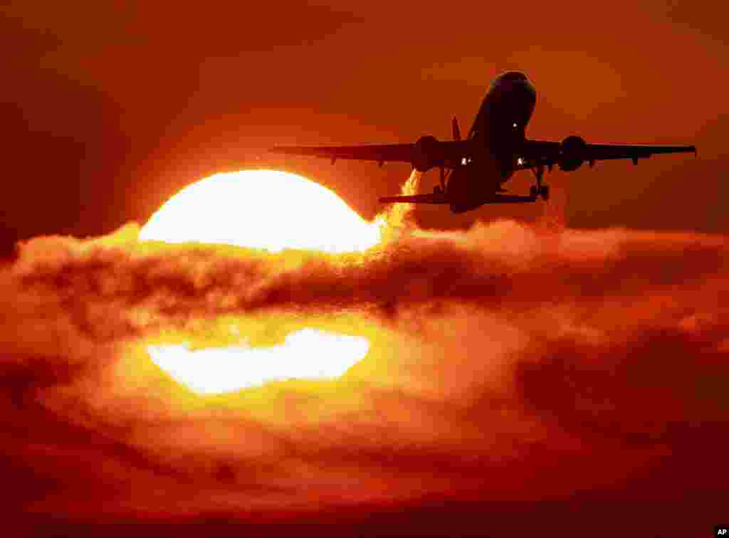 An aircraft passes the rising sun during take-off at the international airport in Frankfurt, Germany.