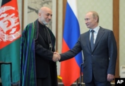 FILE - Russian President Vladimir Putin (R) and Afghan President Hamid Karzai shake hands during a meeting in Beijing, China, June 7, 2012.
