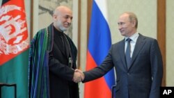 Russian President Vladimir Putin (R) and Afghan President Hamid Karzai shake hands during a meeting in Beijing, China, June 7, 2012. 