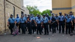 Policajci u Mineapolisu stoje naspram demonstranata koji protestuju zbog smrti Džordža Flojda ispred treće policijske stanice u Mineapolisu, 27. maja 2020.