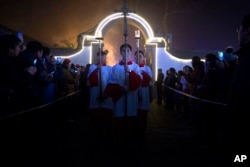 FILE - Cross-bearers process through the church grounds during a Christmas Eve mass at the Southern Cathedral, an officially-sanctioned Catholic church in Beijing, Dec. 24, 2015.