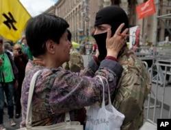 A woman speaks with a volunteer before he sets off for eastern Ukraine to join the ranks of the special battalion "Azov" during a rally in Independence Square in Kiev, Ukraine, June 15, 2014.