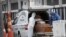 FILE - Funeral workers wearing protective gear as a precaution amid the new coronavirus pandemic push the remains of a COVID-19 victim into a funeral car at a field hospital in Leblon, Rio de Janeiro, Brazil, June 4, 2020. 