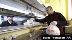 Glen Quadros, pemilik dari restoran Great American Diner & Bar, memeriksa pesanan take away yang dibungkus dengan plastik di restorannya di Seattle, pada 31 Maret 2020. (Foto: AP/Elaine Thompson) 