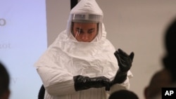 Cpl. Zachary Wicker shows how to put gloves on while in germ-protective gear in Fort Bliss, Texas on October 14, 2014.