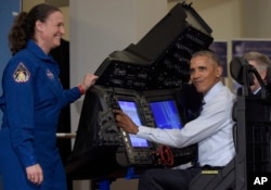 President Barack Obama sits in a flight simulator during a tour of projects at the White House Frontiers Conference at University of Pittsburgh in Pittsburgh, Oct. 13, 2016, as NASA astronaut Dr. Serena Aunon-Chancellor, left, watches.