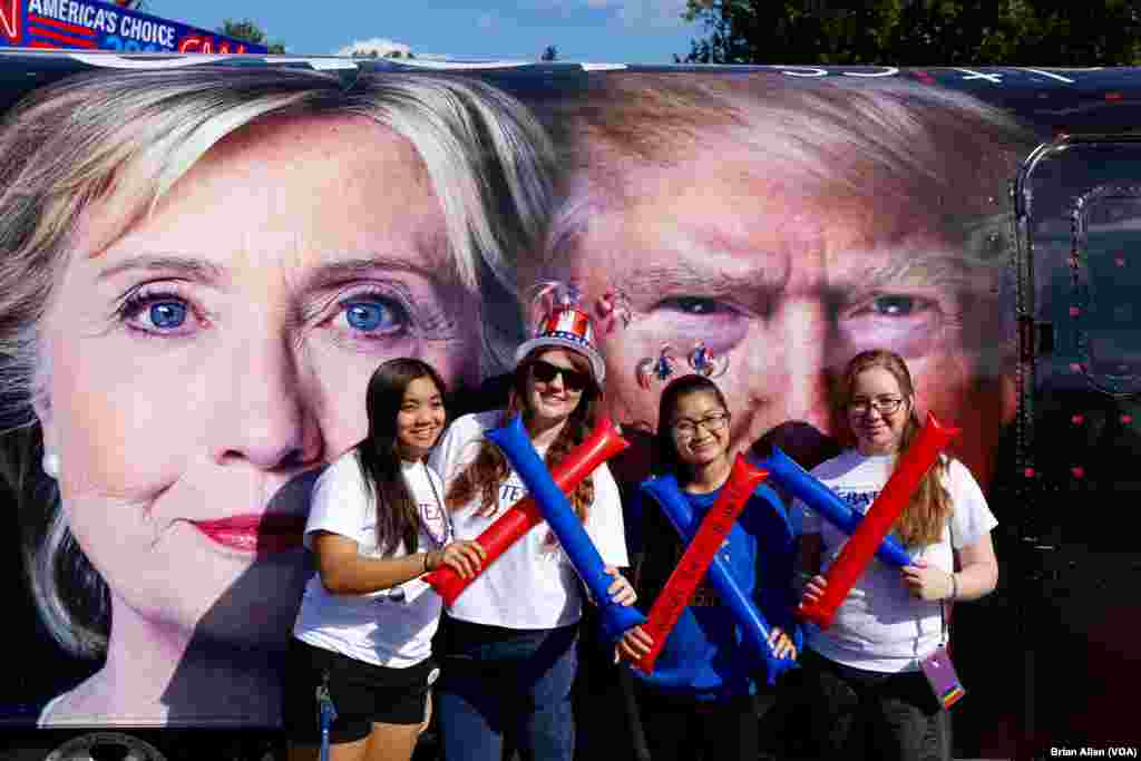 Students pose in front of the faces of presidential candidates Hillary Clinton and Donald Trump. The two will face off against each other in a debate on the Hofstra University campus on Monday night. (B. Allen/VOA)