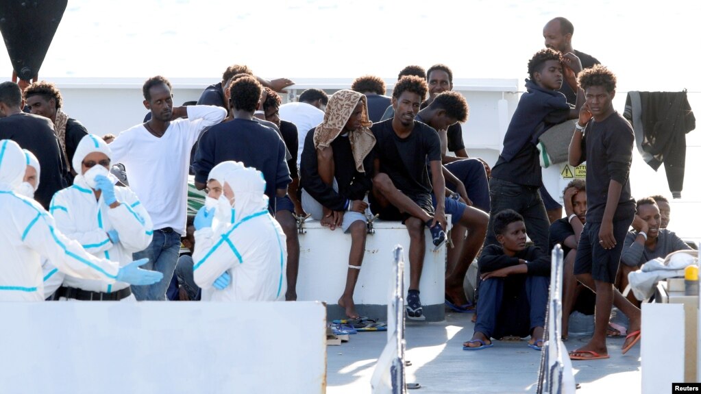 FILE - Migrants wait to disembark from the Italian coast guard vessel "Diciotti" at the port of Catania, Italy, Aug. 22, 2018.