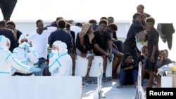 FILE - Migrants wait to disembark from the Italian coast guard vessel "Diciotti" at the port of Catania, Italy, Aug. 22, 2018.