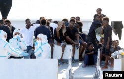 FILE - Migrants wait to disembark from the Italian coast guard vessel Diciotti at the port of Catania, Italy, Aug. 22, 2018.