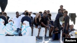 FILE - Migrants wait to disembark from the Italian coast guard vessel "Diciotti" at the port of Catania, Italy, Aug. 22, 2018.