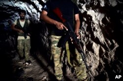 FILE - Fighters with the Free Syrian army leave a cave where they live, in the outskirts of the northern town of Jisr al-Shughur, Syria, west of the city of Idlib, Sept. 9, 2018.