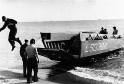 FILE - A navy man jumps from a small landing craft after searching the sea near Palomares, Spain, Feb. 9, 1966.