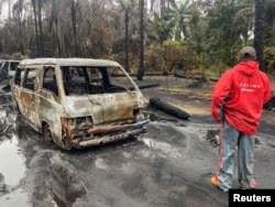 Seorang pria berdiri di lokasi ledakan yang menewaskan lebih dari 100 orang, di lokasi penyimpanan minyak mentah ilegal di hutan Abaezi, Area Pemerintah Daerah Ohaji-Egbema, negara bagian Imo, Nigeria, 24 April 2022. (REUTERS/Tife Owolabi)