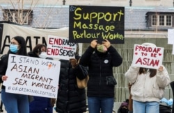 FILE - People hold placards as they gather to protest anti-Asian hate crimes and vandalism, outside City Hall in Toronto, Ontario, Canada, March 28, 2021.