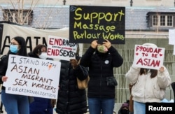 FILE - People hold placards as they gather to protest anti-Asian hate crimes and vandalism, outside City Hall in Toronto, Ontario, Canada, March 28, 2021.