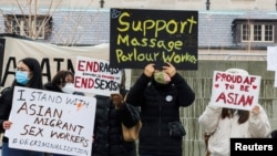 FILE - People hold placards as they gather to protest anti-Asian hate crimes and vandalism, outside City Hall in Toronto, Ontario, Canada, March 28, 2021. 