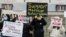 FILE - People hold placards as they gather to protest anti-Asian hate crimes and vandalism, outside City Hall in Toronto, Ontario, Canada, March 28, 2021. 