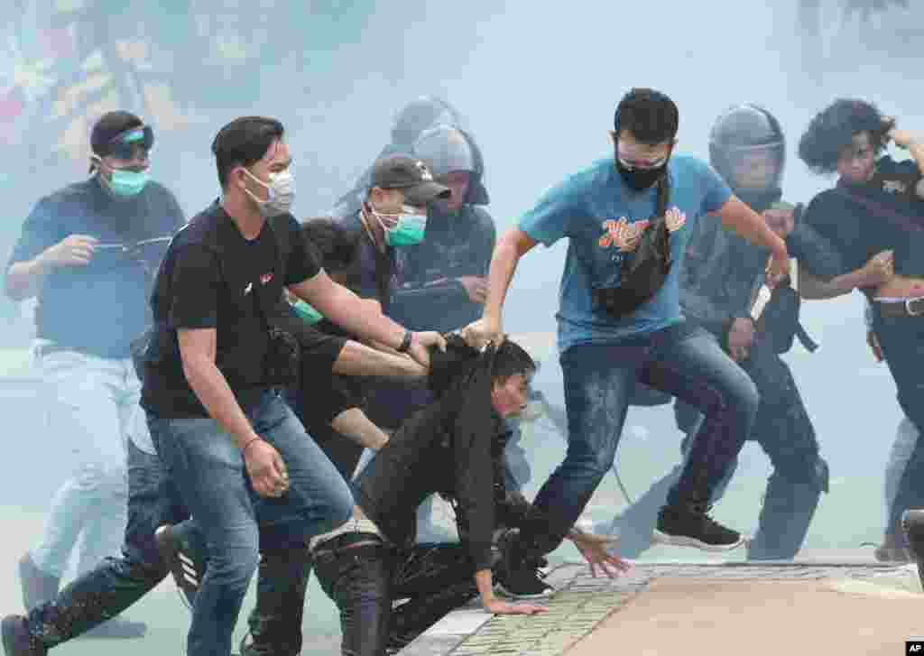 Plain-clothed police officers detain protesters during a rally in Jakarta. Thousands of students and workers staged rallies across Indonesia to protest against a new law they say will cripple labor rights and harm the environment.