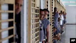 FILE - Prisoners look out from their cells at the Combinado del Este prison during a media tour in Havana, Cuba, Apr. 9, 2013.