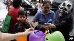 FILE - Children wearing Halloween masks receiving candies and sweets during the "Trick or Treat" tradition.