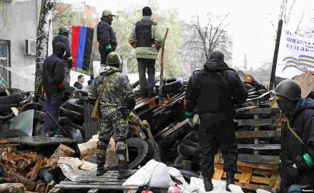 Pro-Russian men stand guard at a barricade near the police headquarters in Slovyansk, April 13, 2014.