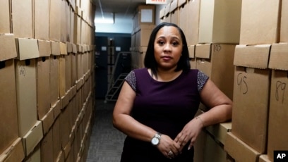 FILE - Fulton County District Attorney Fani Willis poses among boxes containing thousands of cases at her office, on Feb. 24, 2021, in Atlanta.