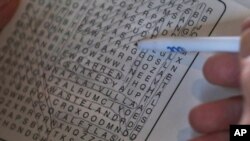 Charles Flagg, who is stricken with Alzheimer's disease, works on a word puzzle at his family home in Jamestown, R.I., Nov. 22, 2019.