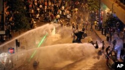 Para aktivis Lebanon menyerukan slogan-slogan anti-pemerintah di tengah semprotan air oleh polisi atas mereka di Beirut (23/8). (AP/Bilal Hussein)