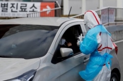 A medical staff member in protective gear prepares to take samples from a visitor at a "drive-thru" testing center for the novel coronavirus disease of COVID-19 in Yeungnam University Medical Center in Daegu, South Korea, March 3, 2020.