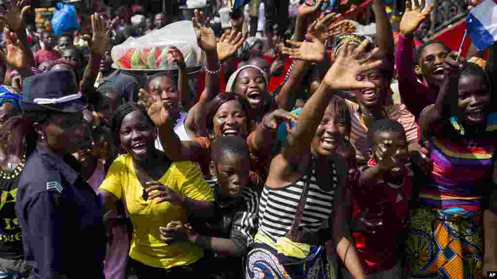 La foule salue le cortège du président français François Hollande et son homologue guinéen Alpha Condé à Conakry, en Guinée, vendredi 28 novembre, 2014.