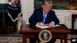 President Donald Trump signs a Presidential Memorandum on the Iran nuclear deal from the Diplomatic Reception Room of the White House, May 8, 2018.