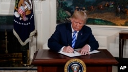 President Donald Trump signs a Presidential Memorandum on the Iran nuclear deal from the Diplomatic Reception Room of the White House, May 8, 2018.