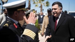 This image released by the media office of the unity government shows Fayez al-Sarraj, right, upon his arrival in Tripoli, Libya, March 30, 2016. He arrived by sea with six deputies to set up a temporary seat of power in a naval base.